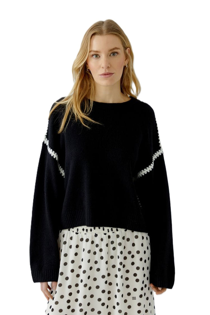 Wollpullover in schwarz von Oui mit Ziernähten in ecru. Der Pullover hat eine überschnittene Schulter und ist kastig geschnitten. 