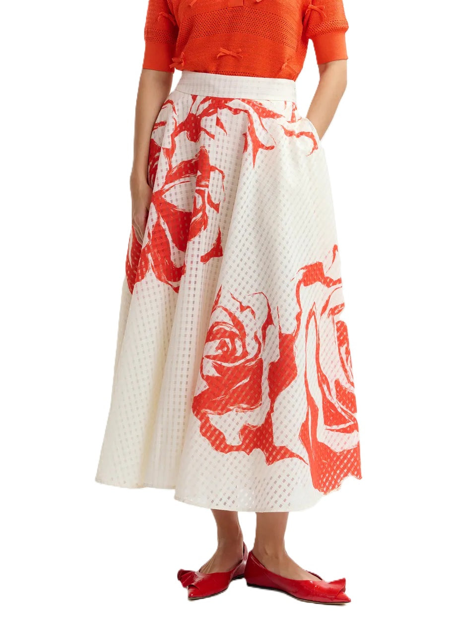 Rock Essentiel Antwerp JANGO MAXI SKIRT in weiß und orange. Dieser Midirock mit tailliertem Bund fällt in eine weite A-Linie, die durch Kellerfalten und verstreute Blumenakzente betont wird. Er ist aus einem glänzenden recycelten Polyestermischgewebe gefertigt und verfügt über praktische Taschen für zusätzliche Funktionalität. Der Rock hat einen hohen Bund und einen verdeckten Reißverschluss.