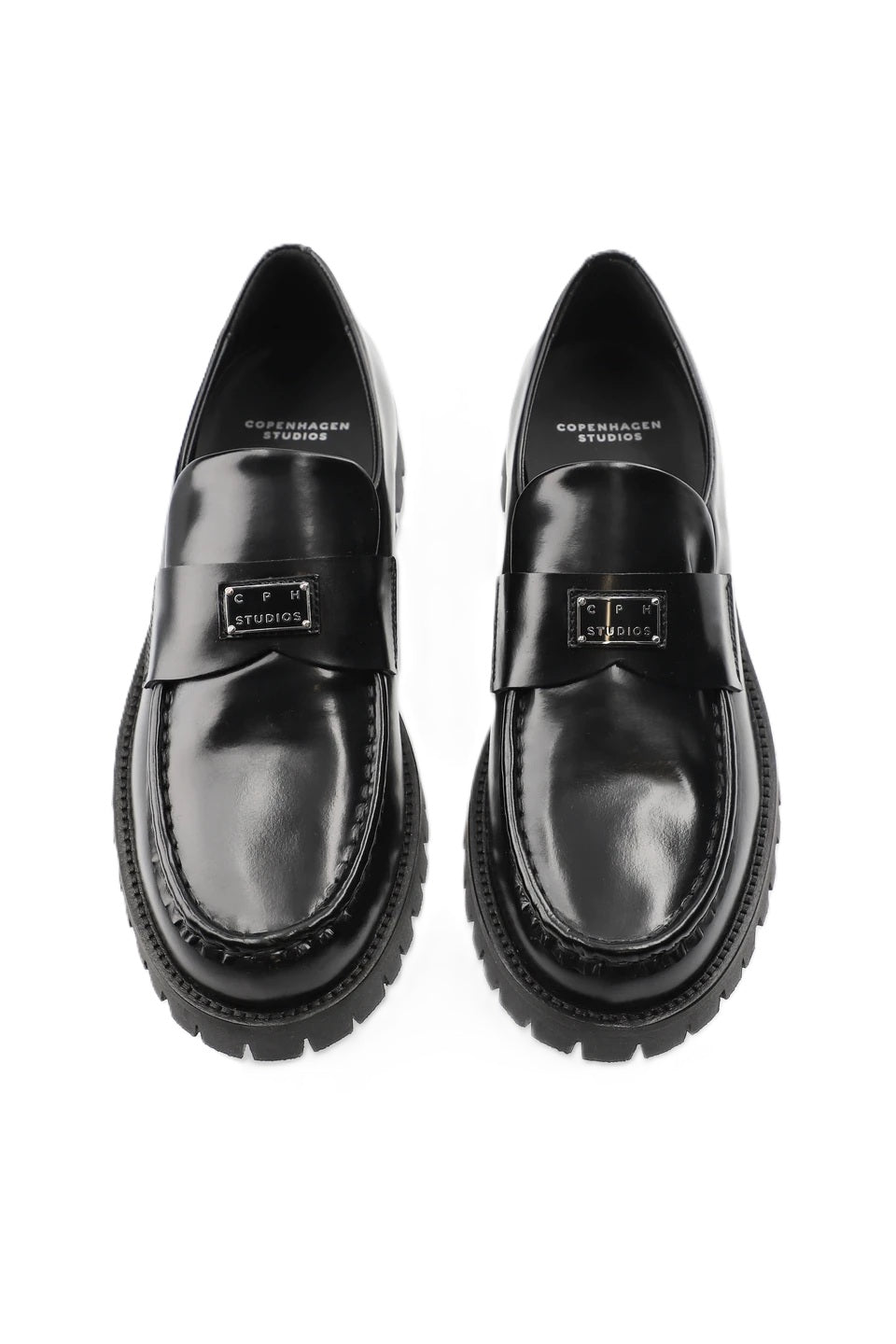 Schuh Copenhagen Studios CPH848 in schwarz. Dieser Loafer ist schmal geschnitten und hat eine glatte, klare Form. Der V-förmige Steg, das glänzende, gebürstete Finish und das Logopatch aus Metall auf der Zunge machen den besonderen Look aus. Das Leder ist sehr weich und der Schuh sehr angenehm zu tragen. 