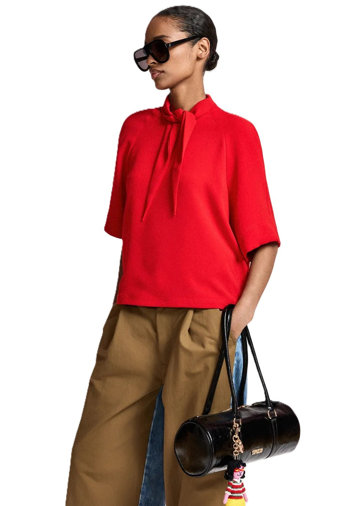 Shirt Essentiel Antwerp KASSIE NECK TIE TOP in rot. Das Oberteil ist locker geschnitten und verfügt über Raglanärmel. Der Stoff fällt fließend und leicht. Eine besonders feminine Note bekommt das Shirt durch den Schalkragen, den man flexibel binden kann. Das Modell hat raffinierte Doppelnähte und einen verdeckten Reißverschluss an der Schulter. 