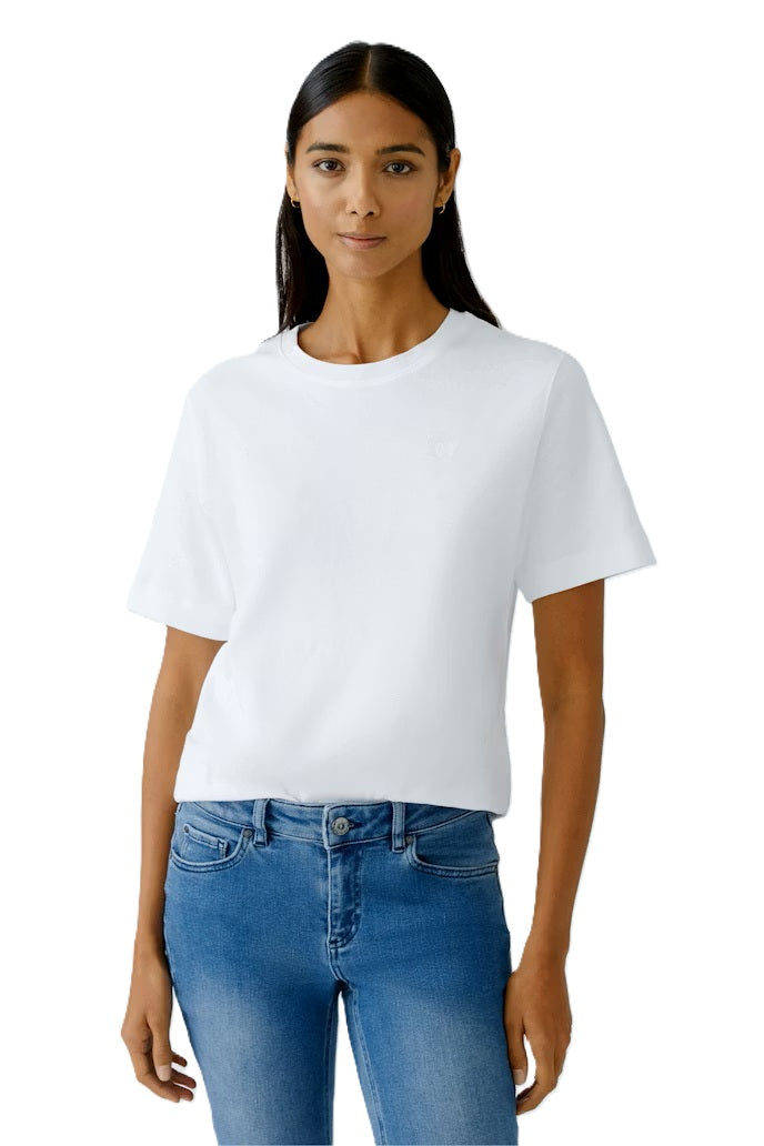 Shirt Oui SVEHA Cloud dancer. Besonderes T-Shirt SVEHA in schwerer, blickdichter Baumwolle. Das Shirt versprüht einen sportlichen Look aund hat einen hohen Tragekomfort. Als kleines Highlight ist ein kleines Herzlogo auf der Brust eingestickt. Das Shirt ist gerade und lässig geschnitten