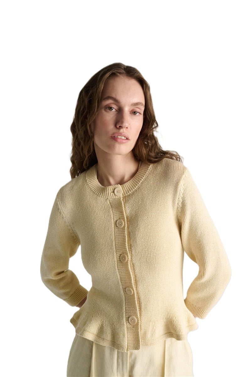 Strickjacke Dorothee Schumacher COTTON CANDY Cardigan. Der kurze Cardigan in beige ist aus weicher Baumwolle gefertigt und hat einen ausgestellten Schnitt. Der Cardigan hat einen verspielten Volant-Effekt am Saum und einen Rundhalsausschnitt. 