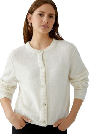 Strickjacke Oui Ilaya in ecru. Kuschelig weiche Garnmischung mit glatt gestrickter Oberfläche und markanten Outside Seams. Lässiger, leicht verkürzter Schnitt mit zurückversetzter Schulternaht. Rundhalsausschnitt, lange Ärmel und Knopfleiste mit Knöpfen in Hornoptik.