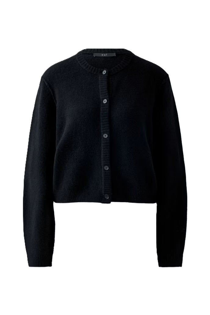 Strickjacke Oui Ilaya in Black. Kuschelig weiche Garnmischung mit glatt gestrickter Oberfläche und markanten Outside Seams. Lässiger, leicht verkürzter Schnitt mit zurückversetzter Schulternaht. Rundhalsausschnitt, lange Ärmel und Knopfleiste mit Knöpfen in Hornoptik.
