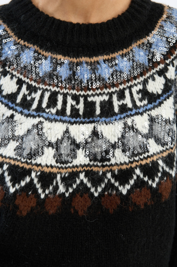 Dunkelblauer Strickpullover VAFFIE von Munthe mit nordisch inspiriertem Muster, dezenten Pailletten und tief angesetzten Ballonärmeln. Der Pullover hat einen Rundhalsausschnitt und ein eingestricktes Munthe-Logo. 