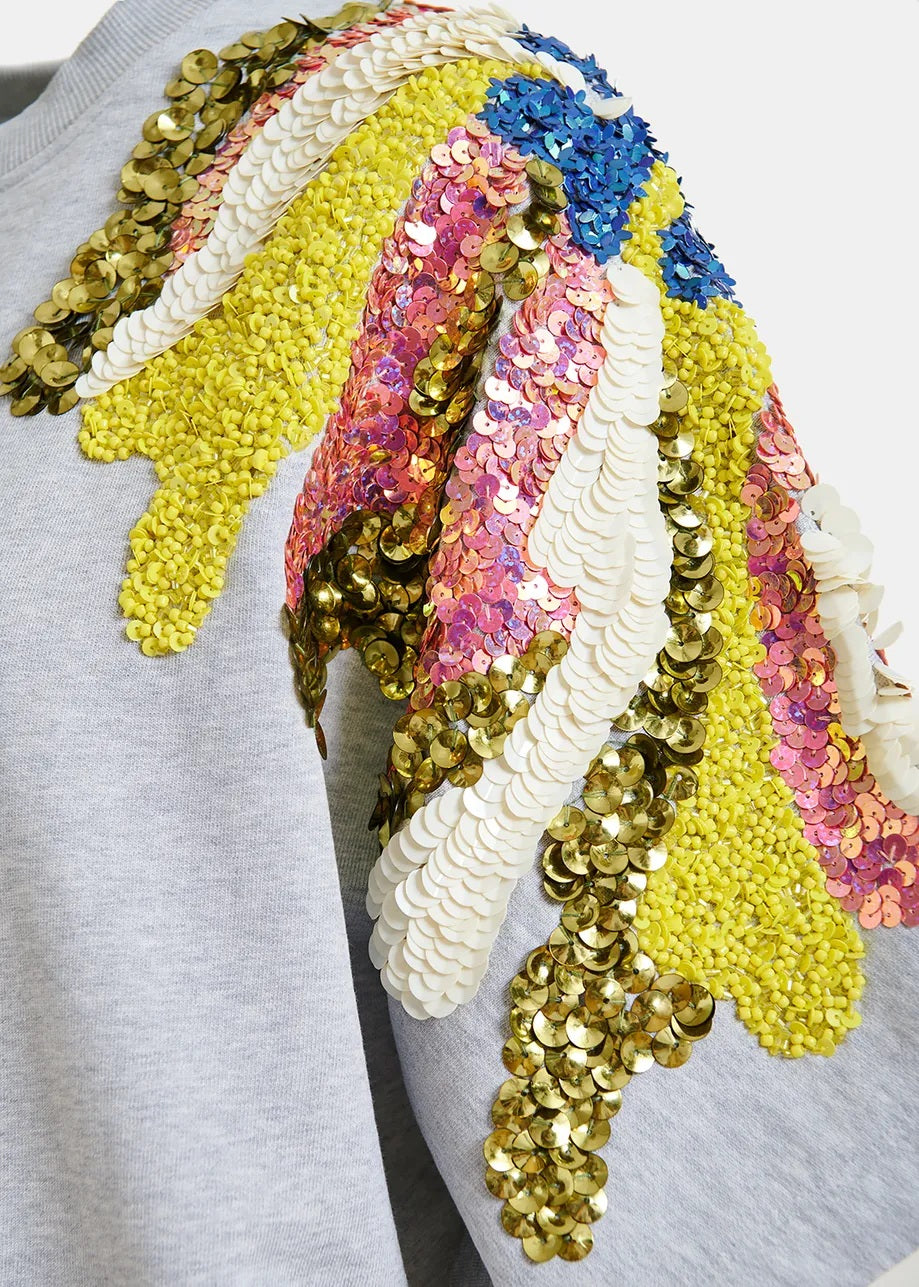 Sweatshirt Essentiel Antwerp JADDA EMBROIDERED SWEATSHIRT. Das Sweatshirt aus reiner Baumwolle ist locker und kastig geschnitten und verfügt über überschnittene Schultern und kurze Ärmel. Es ist mit auffälligen bunten Pailletten- und Perlenverzierungen an den Schultern verziert. Doppelte Nähte verleihen dem Design einen coolen Look. 