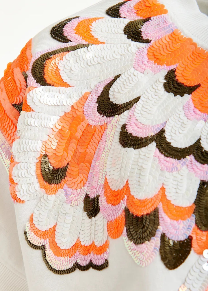 Sweatshirt von Essentiel Antwerp JOLIES EMBROIDERED SWEATSHIRT. Das Sweatshirt hat Pailletten und überschnittene Ärmel. Es ist kastig in den Farben orange und ecru. 