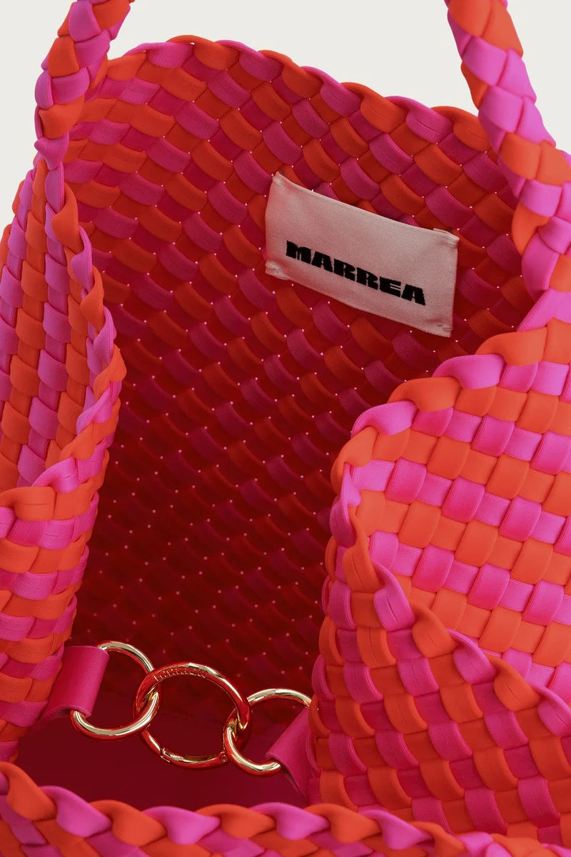 Tasche Marrea Medium bella vita. Diese Tasche in pink orange besticht durch ihre besondere, handgewebte Optik und verbindet lässige Eleganz mit dem modernen Strandlook. Die Größe bietet genügend Raum für alle wichtigen Essentials. Sie hat zwei Top-Griffe und goldene Details, wie den Hakenverschluss und eine Innentasche zum Verschließen. 