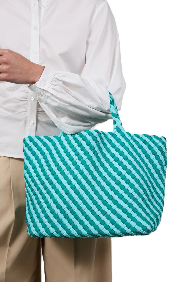 Tasche Marrea Medium Vista Mare. Diese Tasche in türkis und blau besticht durch ihre besondere, handgewebte Optik und verbindet lässige Eleganz mit dem modernen Strandlook. Die Größe bietet genügend Raum für alle wichtigen Essentials. Sie hat zwei Top-Griffe und goldene Details, wie den Hakenverschluss und Innentasche.